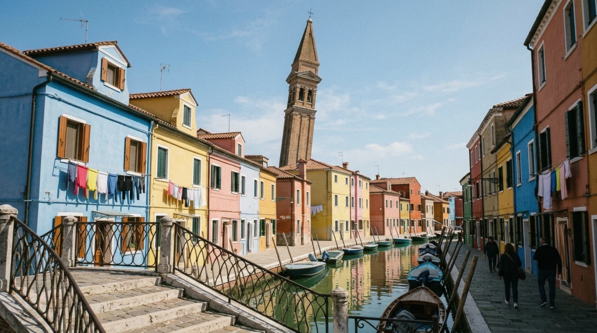 The leaning brick bell tower of Burano above the painted houses, reached by public boat or tour