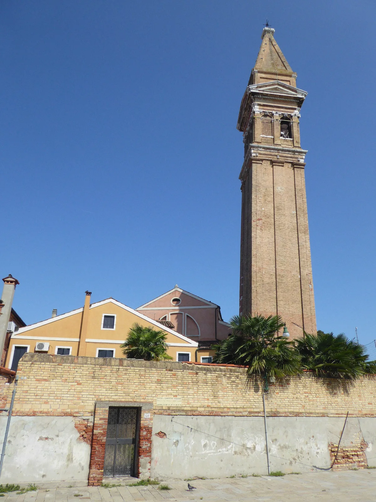 The leaning campanile of Burano above painted houses on the islands half of the Venice in a day combination tour