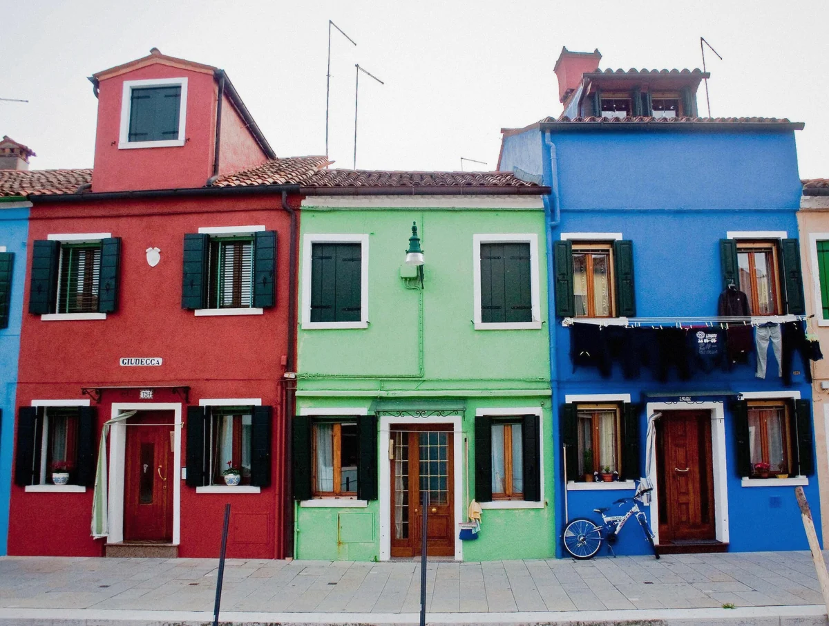 Painted houses over a canal in Burano, the island most travellers call the highlight of a Murano and Burano tour